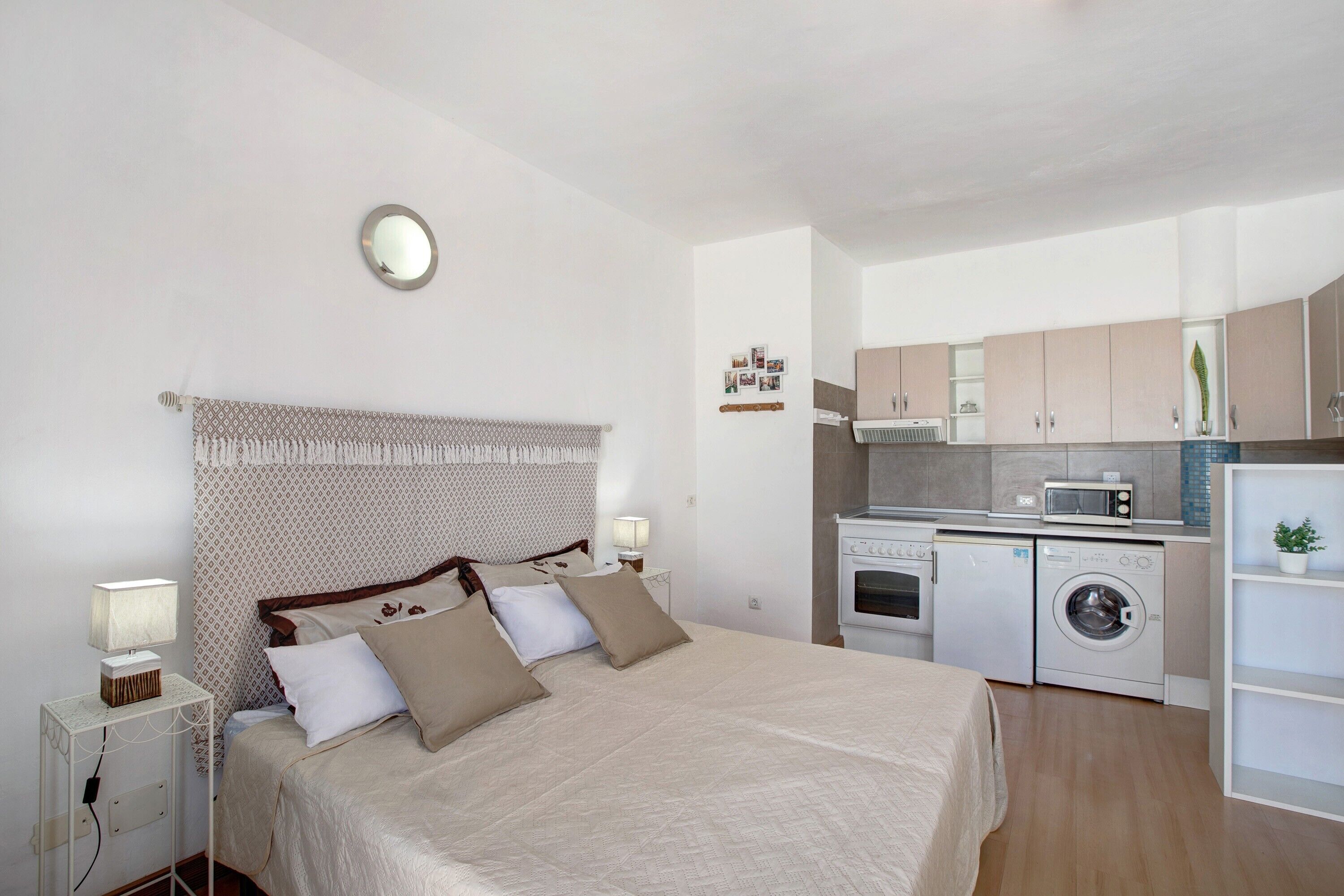 Une chambre comprenant un lit, une table de chevet et une petite kitchenette équipée d’un four à micro-ondes et d’un lave-linge.