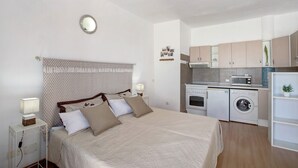 A bedroom with a bed, bedside table, and a small kitchenette with a microwave and washing machine. - Holiday Home 'Estudio 4 Costa Adeje' with Wi-Fi (Adeje)
