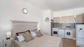 Une chambre comprenant un lit, une table de chevet et une petite kitchenette équipée d’un four à micro-ondes et d’un lave-linge.