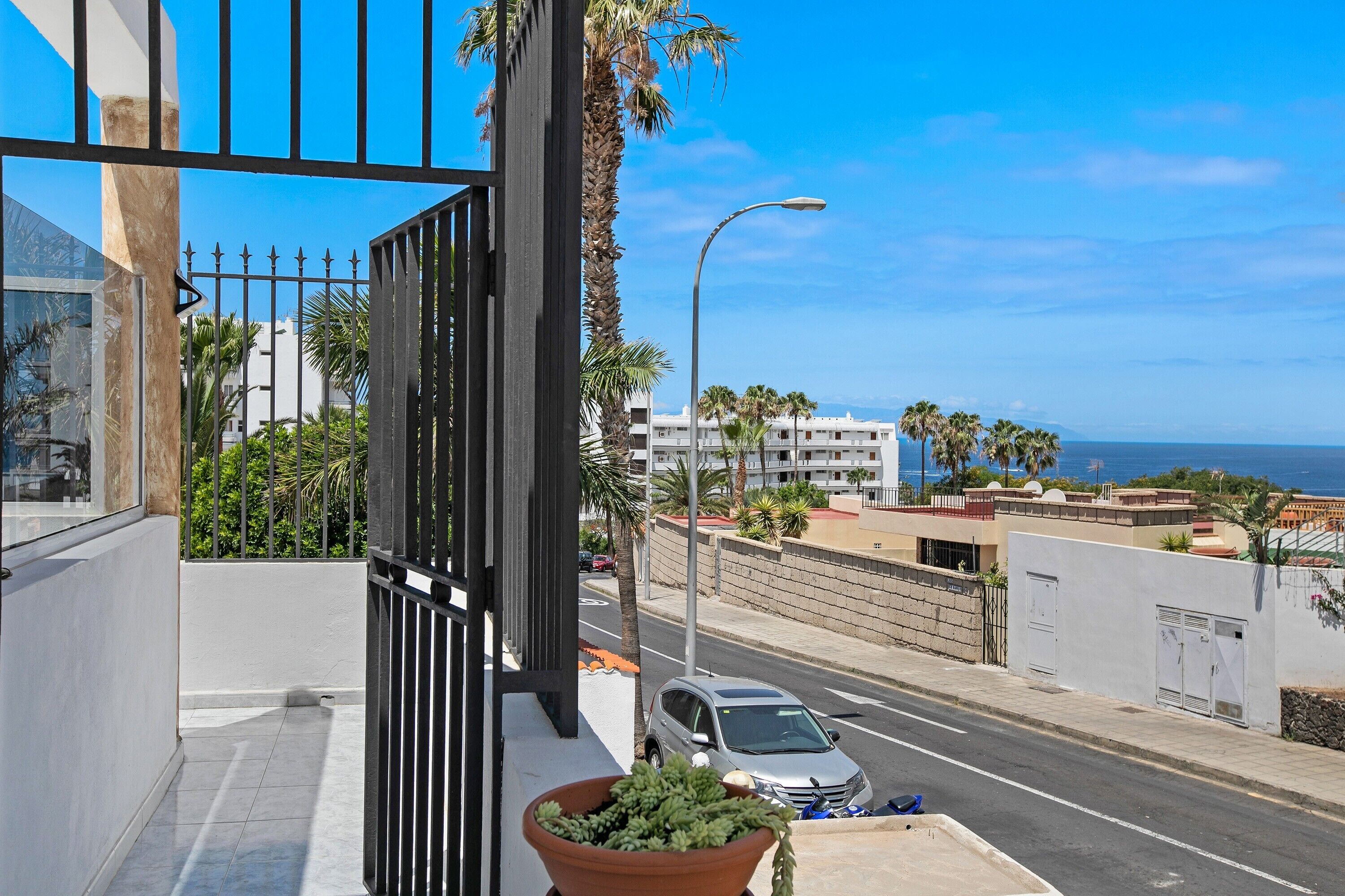 A balcony with a view of a road, a car, and buildings in the distance.