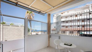 En balkon med et hvidt bord og stole, havudsigt og bygninger med balkoner i baggrunden.