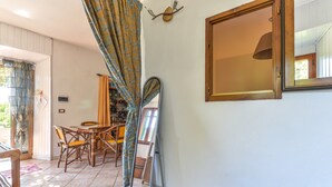 Una habitación con una mesa de comedor, sillas, un espejo y una ventana con cortinas.