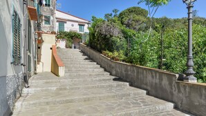 Una escalera de piedra que lleva a un edificio con techo rojo y contraventanas verdes.