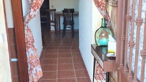 A hallway with patterned curtains, a tiled floor, and a table with a vase and a book.