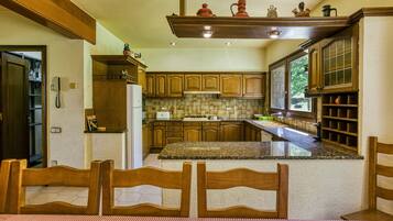 Una cocina con armarios de madera, encimera de granito y una zona de comedor con mantel a cuadros.