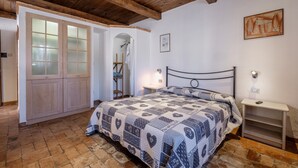 A bedroom with a bed, wooden wardrobe, and a small bedside table.