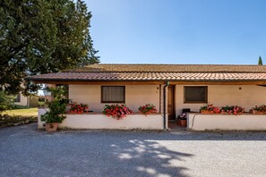 Un bâtiment avec un toit recouvert de tuiles, une porte, des fenêtres et des jardinières.