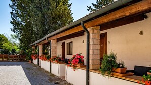 A building with a covered porch, potted plants, and a gravel driveway.
