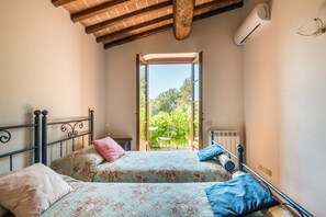Une chambre avec deux lits, un plafond en bois, un appareil de climatisation et une vue sur la verdure environnante.