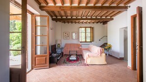 Un soggiorno luminoso con soffitto in legno, un divano, un tavolino da caffè e vista sull'esterno.