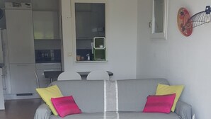 Een woonkamer met een grijze bank, een ronde witte tafel en een groene pluchen zitbal.