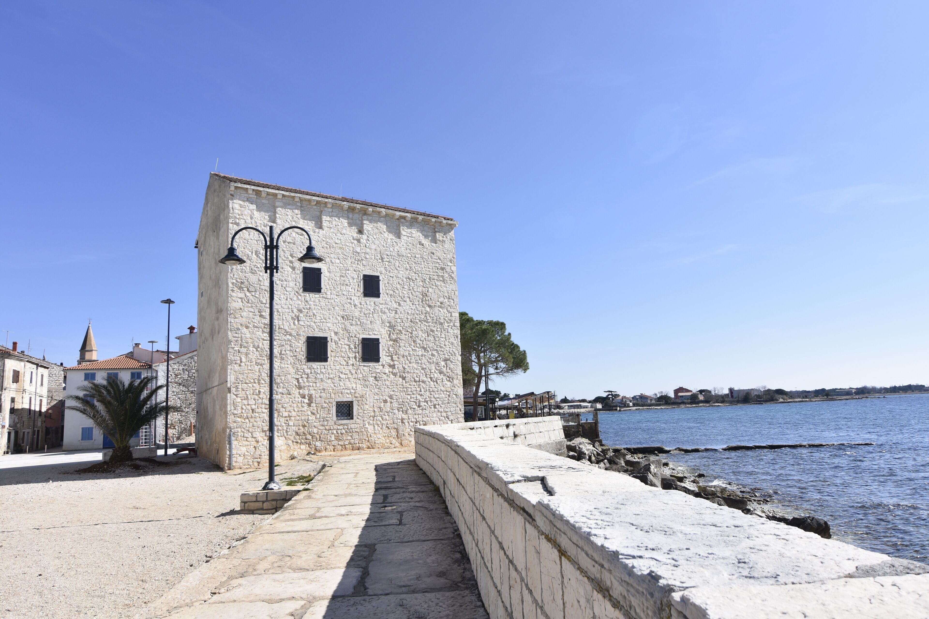 Un edificio de piedra con una escalera que da a la costa.
