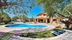 Une piscine entourée de chaises longues, avec une maison en arrière-plan.