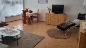 A living room with a dining area, a TV, and a wheelchair.