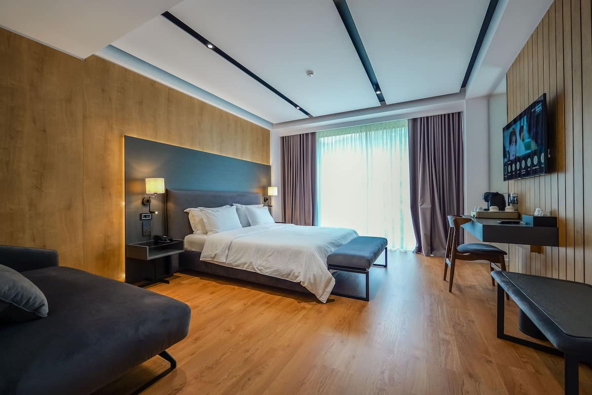 Moderni hotellihuone, jossa on suuri sänky, yöpöydät, työpöytä ja televisio.