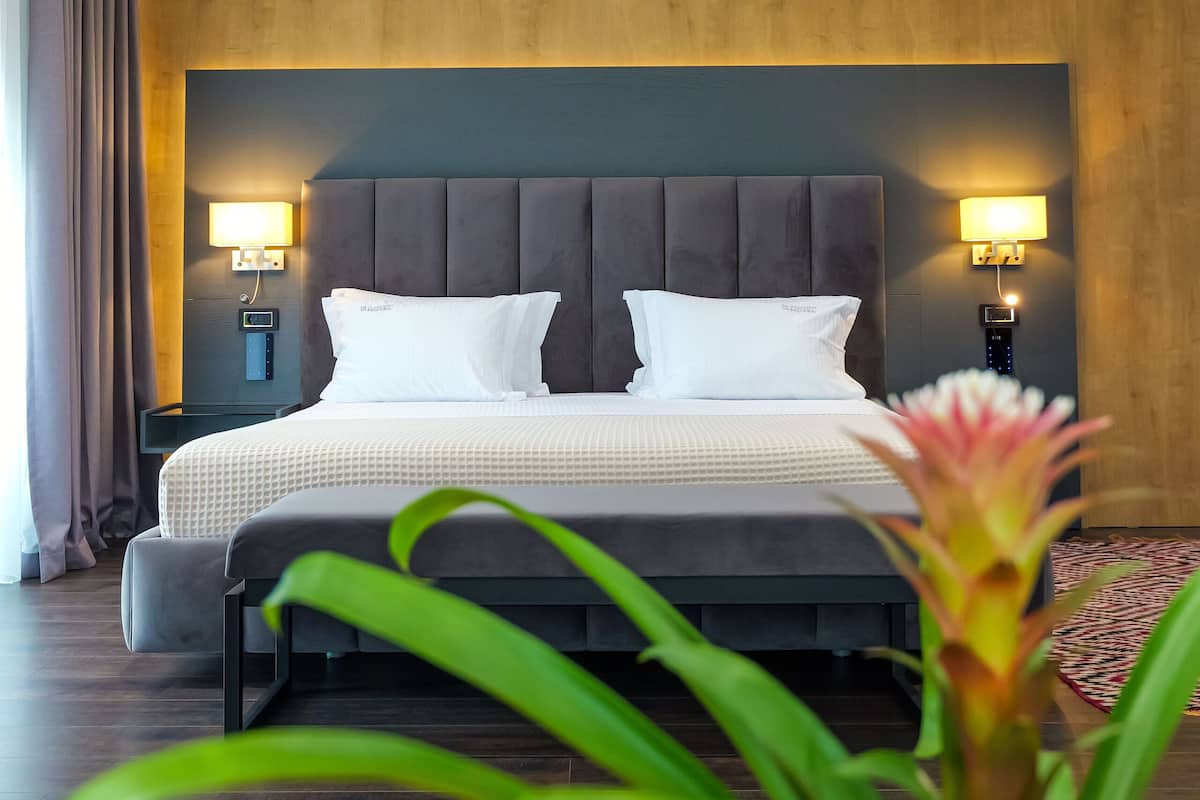 Moderni hotellihuone, jossa on suuri sänky, puupaneloidut seinät ja kaksi yöpöytävalaisinta.