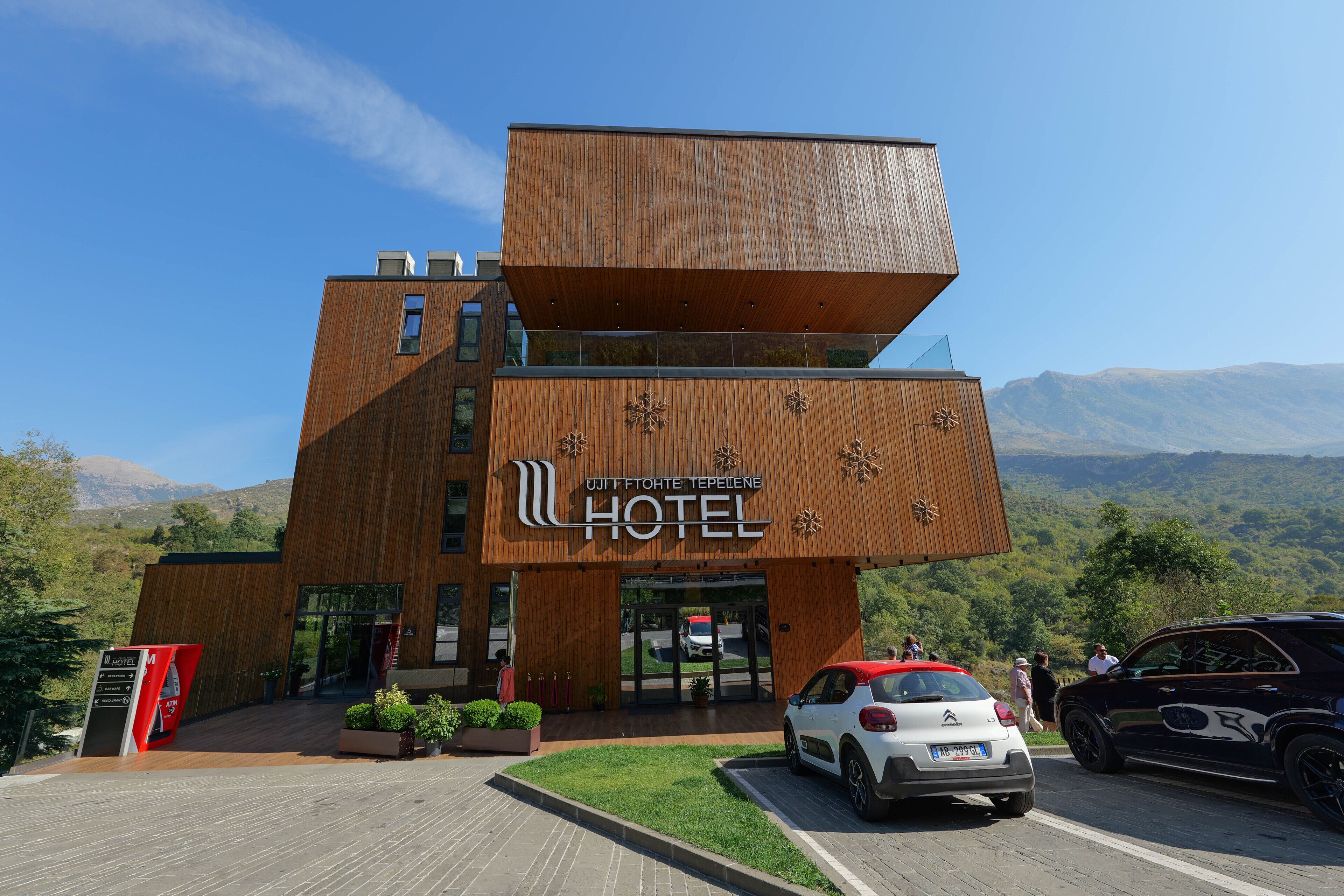 A modern hotel with a unique wooden facade and a sign in a foreign language.