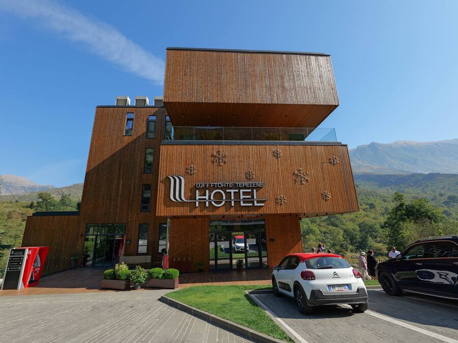 A modern hotel with a unique wooden facade and a sign in a foreign language.
