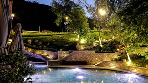 A nighttime swimming pool with surrounding steps and lighting. - Uji i Ftohte Hotel (Qendër Tepelenë)