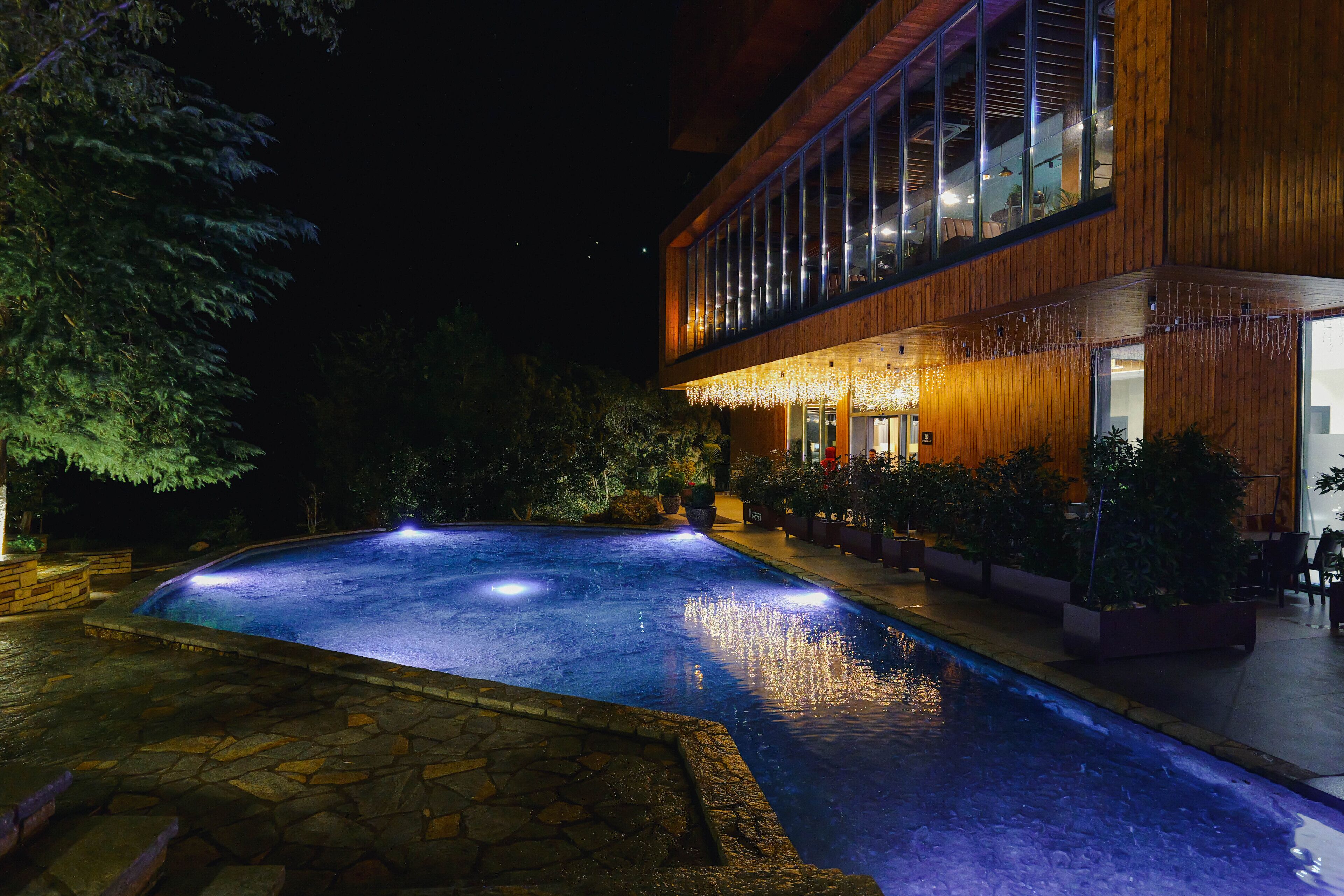 Vista notturna di una zona piscina con un edificio in legno sullo sfondo.