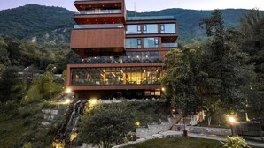 A modern multi-story building with glass balconies and a waterfall feature at the base. - Uji i Ftohte Hotel (Qendër Tepelenë)