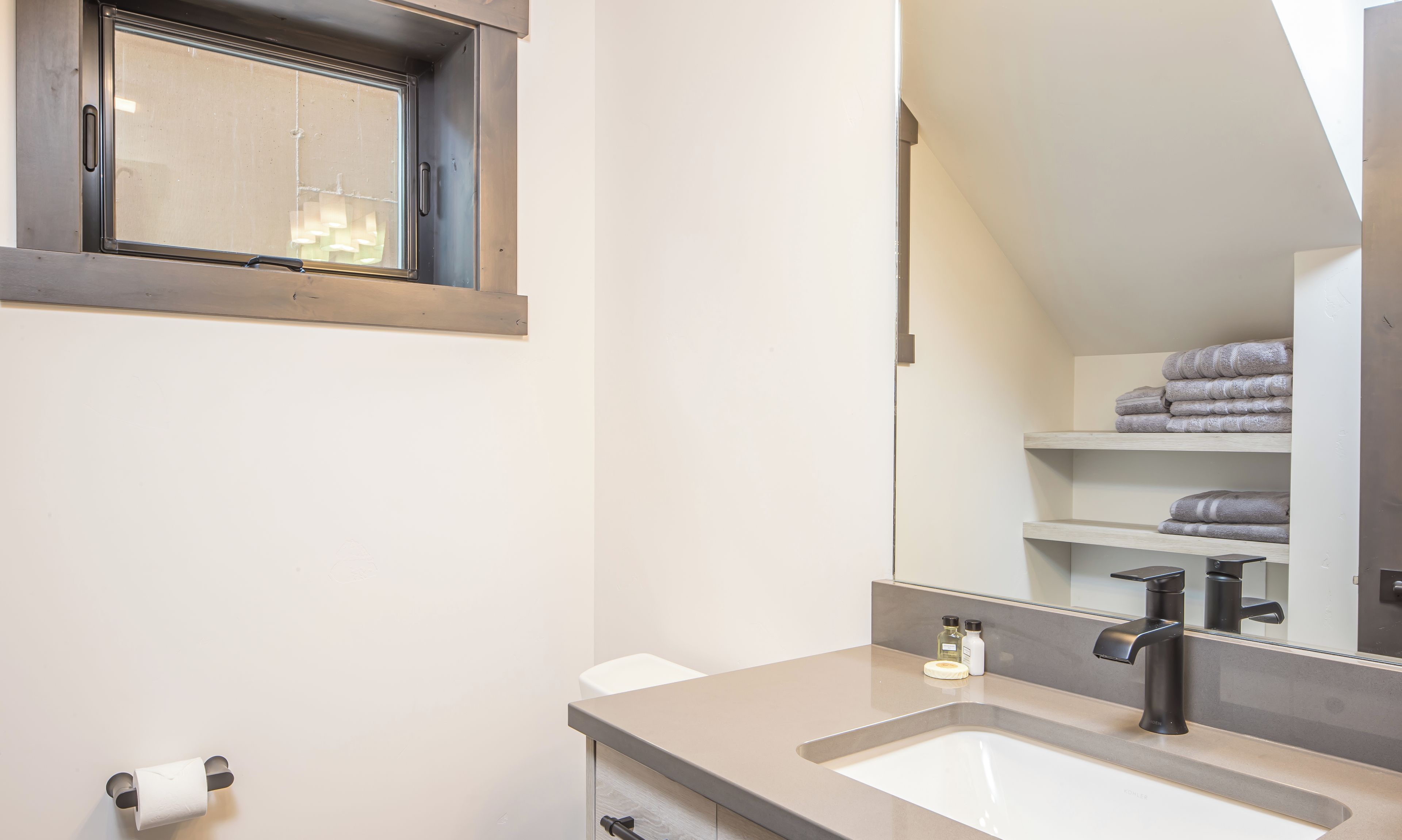 Une salle de bain moderne avec un grand miroir, un lavabo et une fenêtre.