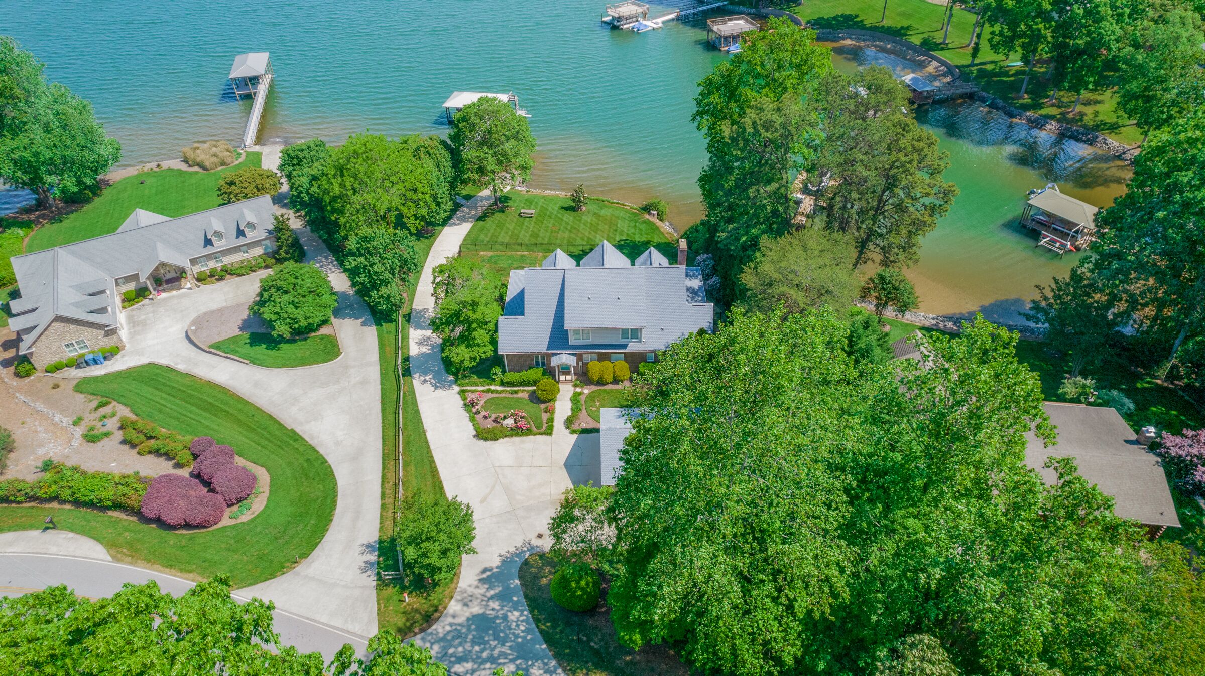 An aerial view of a residential area with a large house, a dock, and a lake.