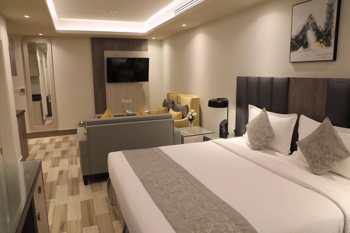 Ein modernes Hotelzimmer mit einem großen Bett, einer Couch, einem Fernseher und einem Spiegel.