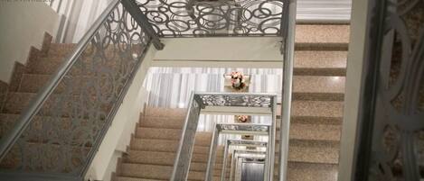 A grand staircase with ornate metal railings and a mirrored wall reflecting the steps.