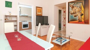 Un soggiorno moderno con zona pranzo, angolo cottura e televisione.