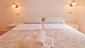 Un letto matrimoniale con una coperta a motivi, due comodini e lampade a parete.