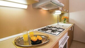Una cucina con fornello a gas, lavello e un vassoio con succo d'arancia e fettine d'arancia.