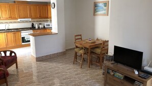 A compact living space with a kitchen, dining area, and a TV stand with books.