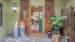 Una entrada de madera con una puerta verde, suelo de piedra y un felpudo con la palabra 'HELLO'.