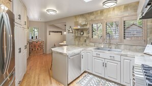 Una cocina moderna con tragaluz, armarios blancos, un refrigerador de acero inoxidable y un lavavajillas integrado.