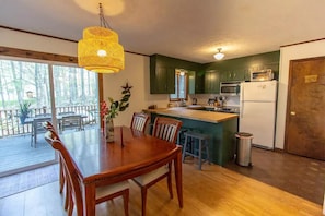 A kitchen with wooden cabinets, a central island, a microwave, and a refrigerator. - Mountain Cabin in Pocono Resort (Gouldsboro)