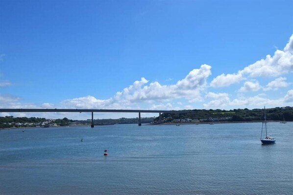 A river with a bridge, boats, and a sailboat.