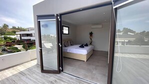 Une chambre moderne avec un lit, une plante en pot et une vue sur un bâtiment à l’extérieur.