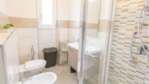 A bathroom with a toilet, bidet, and a glass-enclosed shower area. - Cittadella Apartment (Florence)