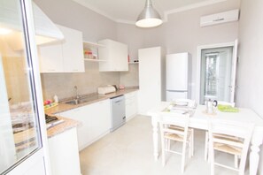 A modern kitchen with white cabinetry, a built-in dishwasher, and a dining area with a table and chairs. - Cittadella Apartment (Florence)