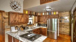 A kitchen with wooden cabinets, a stainless steel refrigerator, a stove, and a microwave.