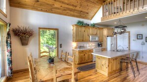 Une cuisine spacieuse dotée de meubles en bois, d’un îlot central et d’un coin repas avec une table et des chaises en bois.