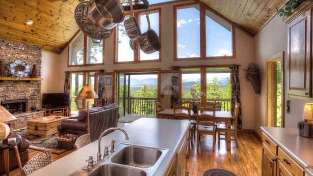 Une cuisine spacieuse dotée d’un grand îlot central, de planchers en bois et de grandes fenêtres offrant une vue sur l’extérieur.