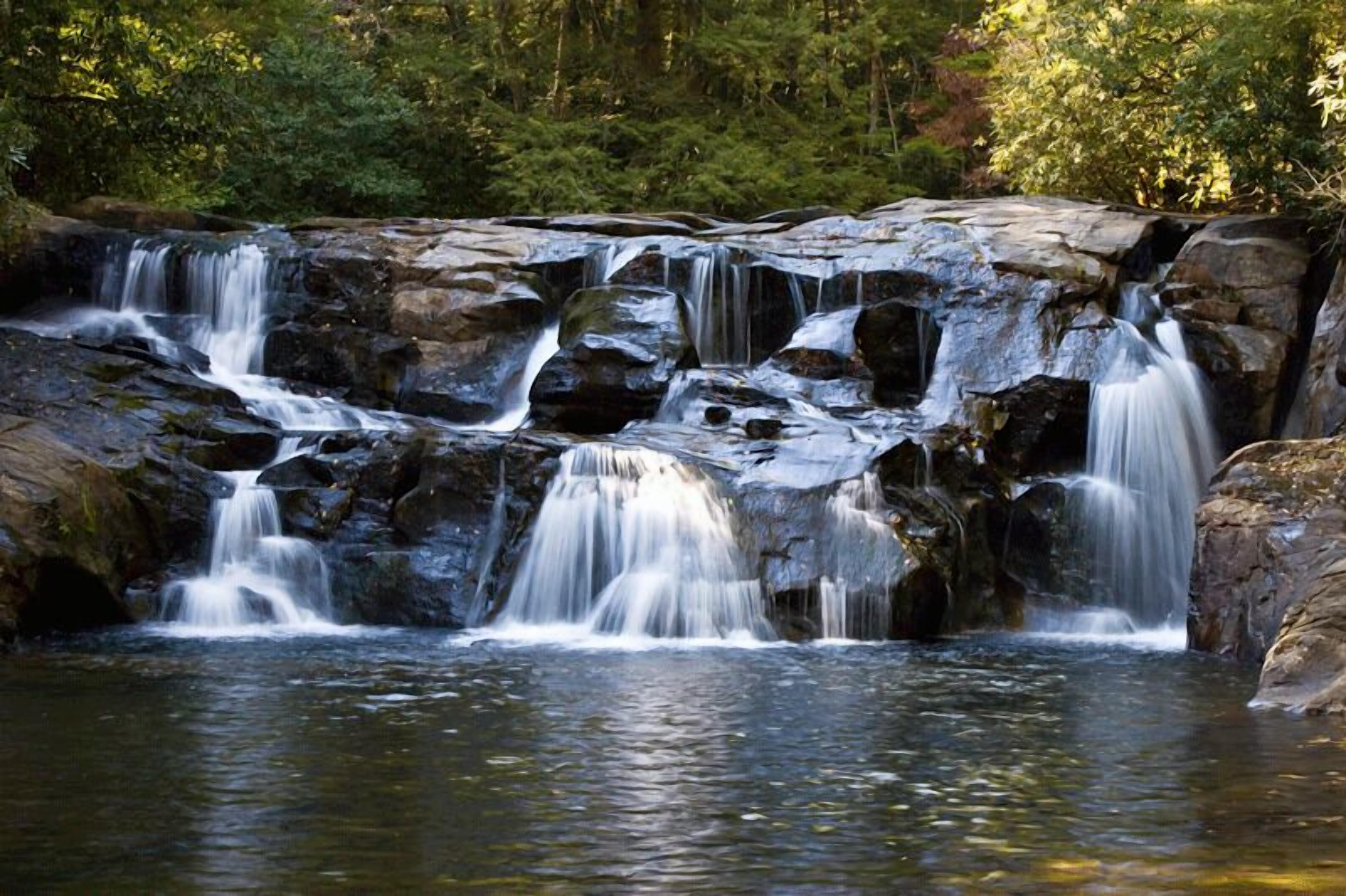 Ein mehrstufiger Wasserfall in bewaldeter Landschaft.