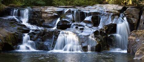 Ein mehrstufiger Wasserfall in bewaldeter Landschaft.
