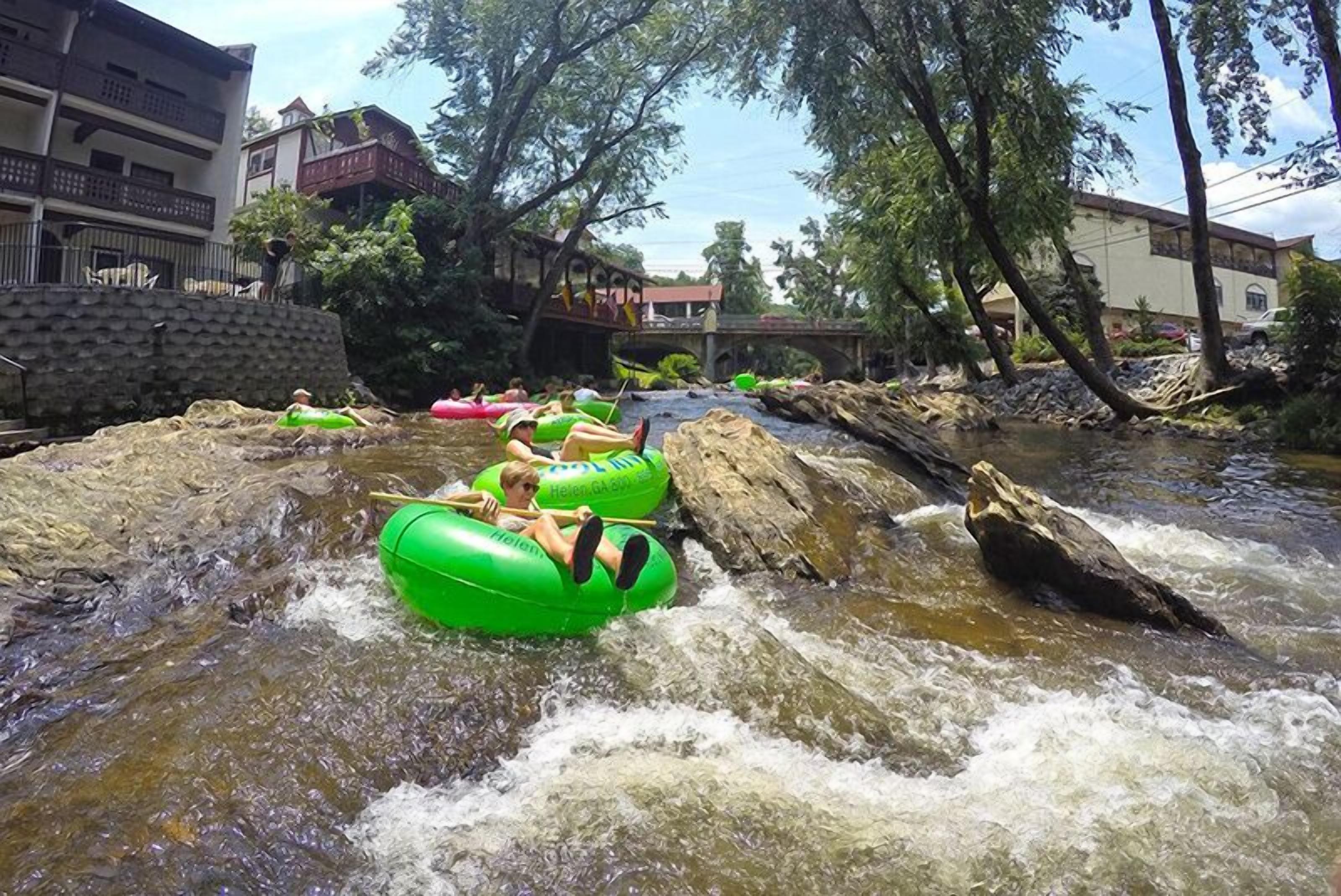 A river with people in green inflatable tubes.