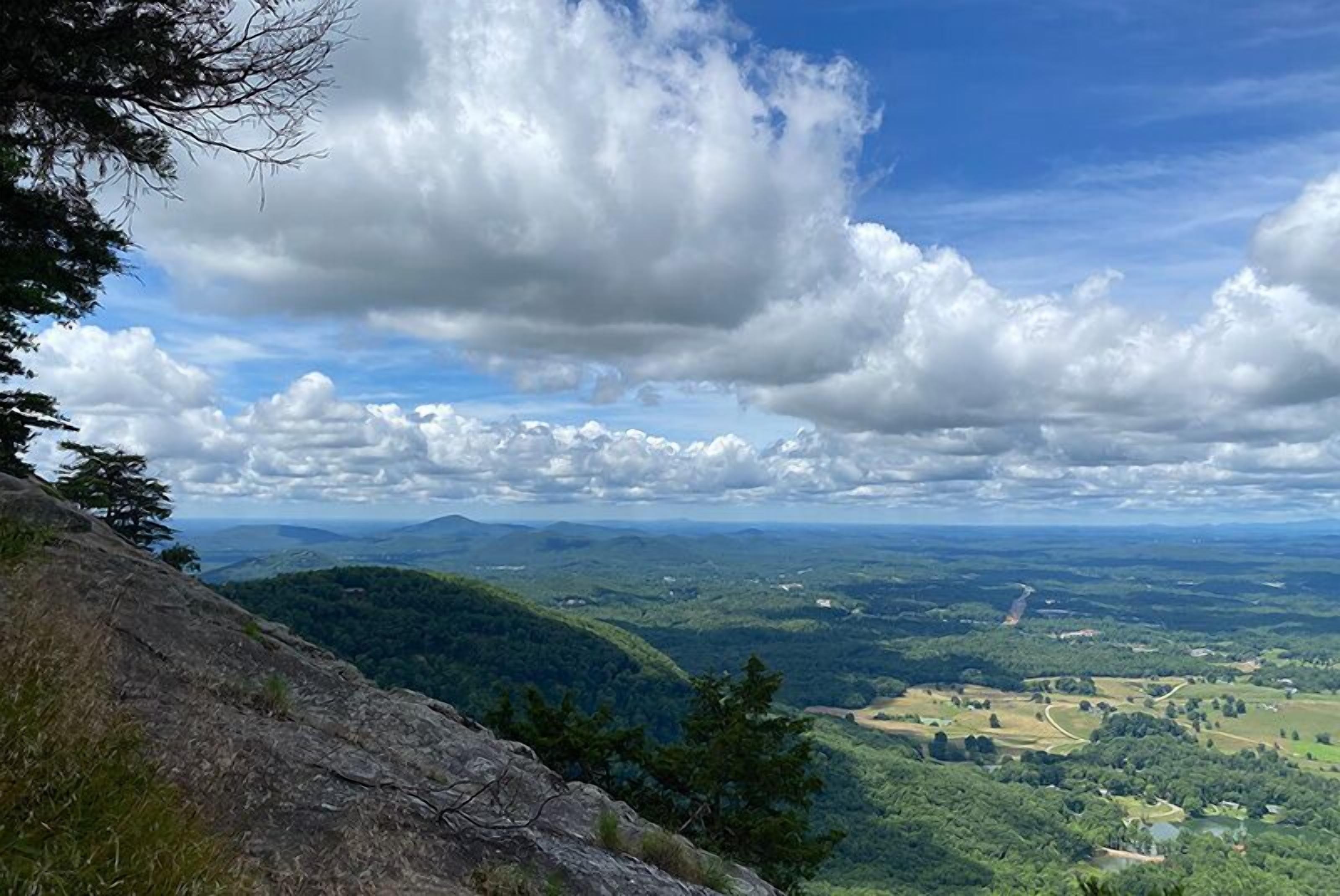 A panoramic view of a mountainous landscape with a clear sky and scattered clouds.