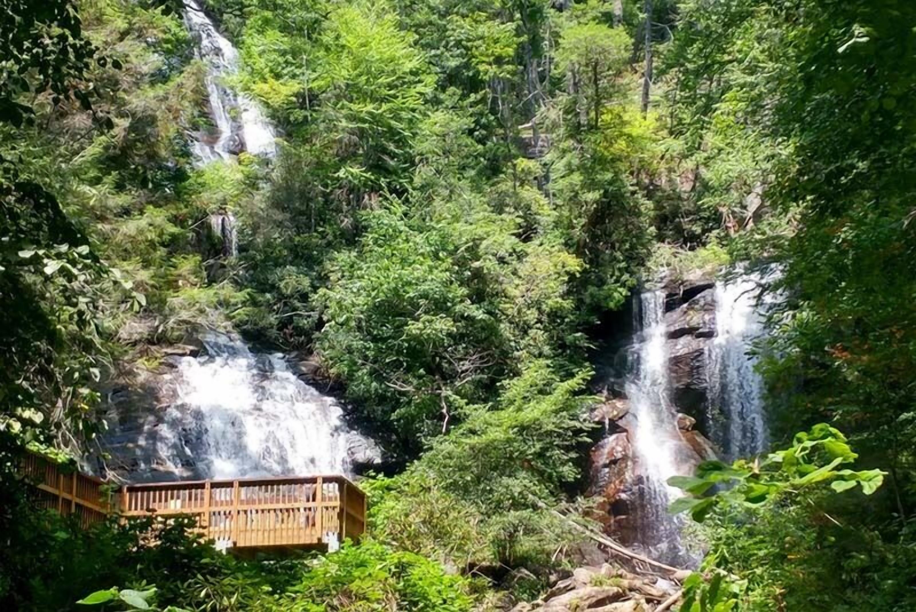 A wooden viewing platform overlooking a waterfall surrounded by dense forest.