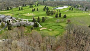 A golf course with a clubhouse, a pond, and surrounding wooded areas. - Relaxing Retreat - Close to Downtown Harbor Springs and Ski Resorts! (Harbor Springs)