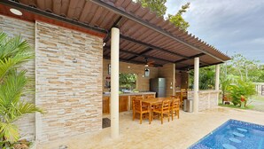 A covered outdoor kitchen with a pool.